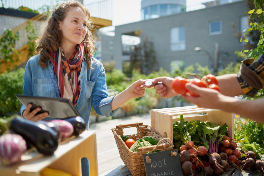 Friendly woman tending an organic vegetable stall at a farmer